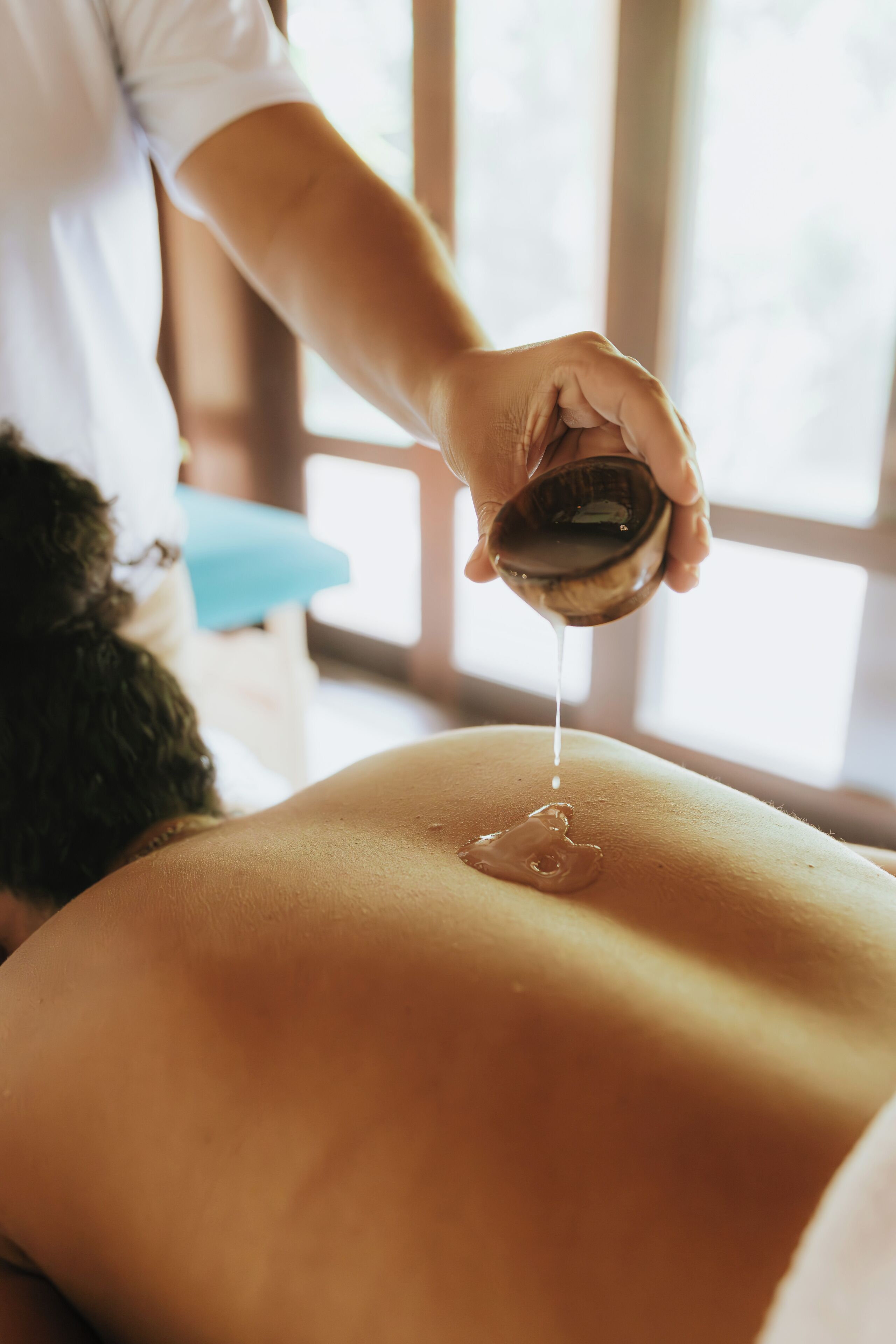 A person receiving a massage with oil being applied to their back.