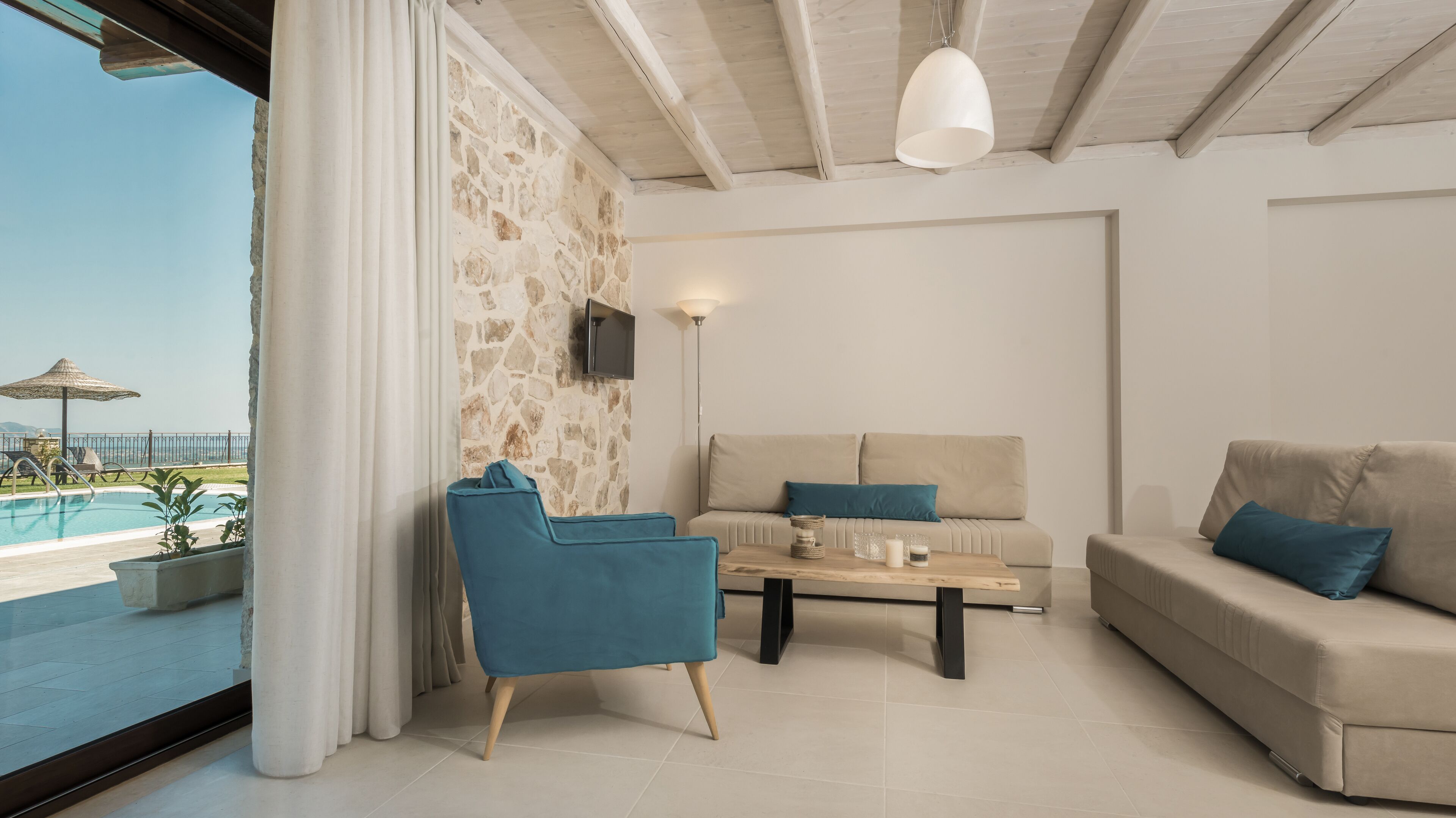 Un salon moderne avec un mur en pierre, un canapé, un fauteuil bleu et une table basse.