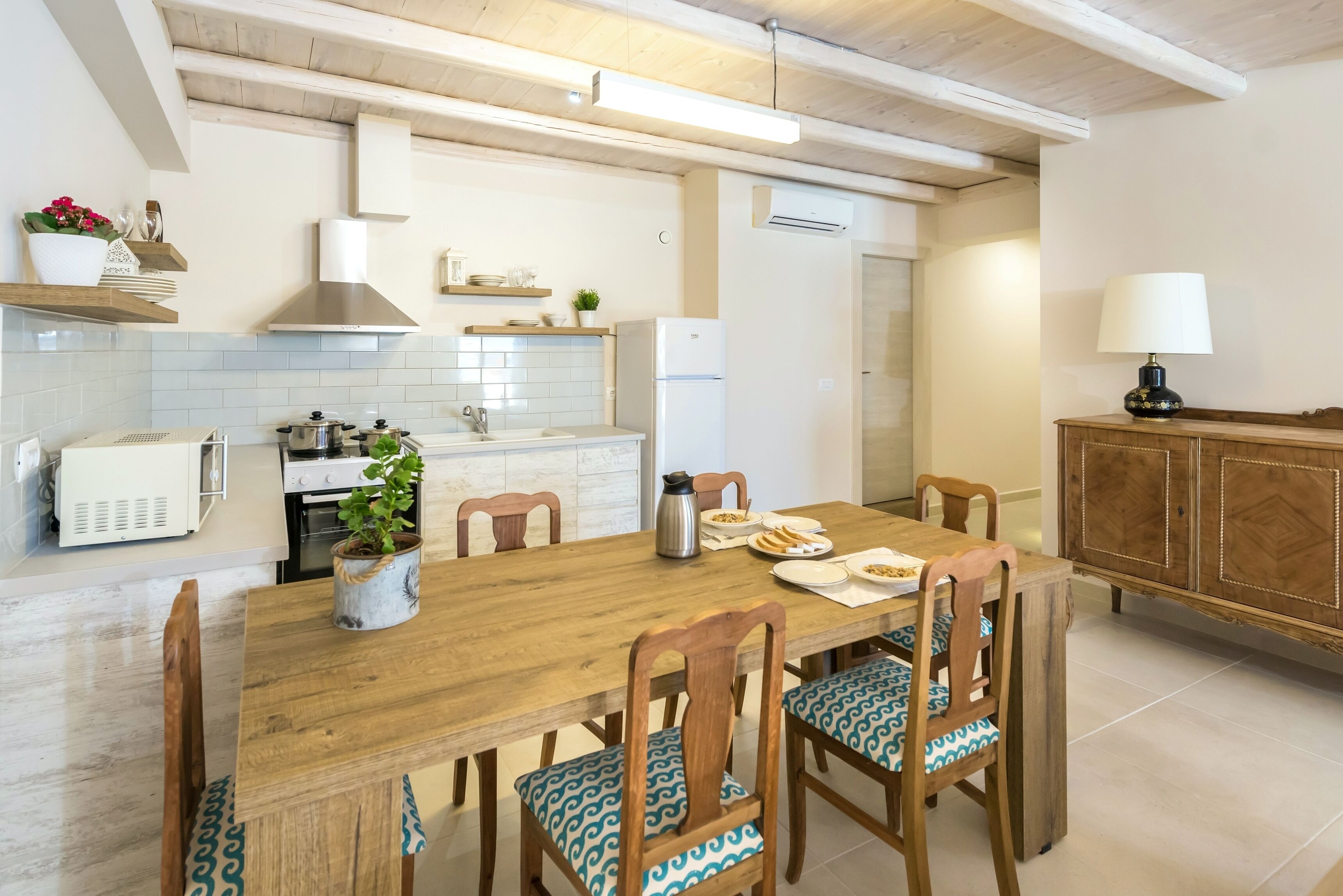 Une cuisine moderne avec une table à manger en bois, des chaises et un réfrigérateur.
