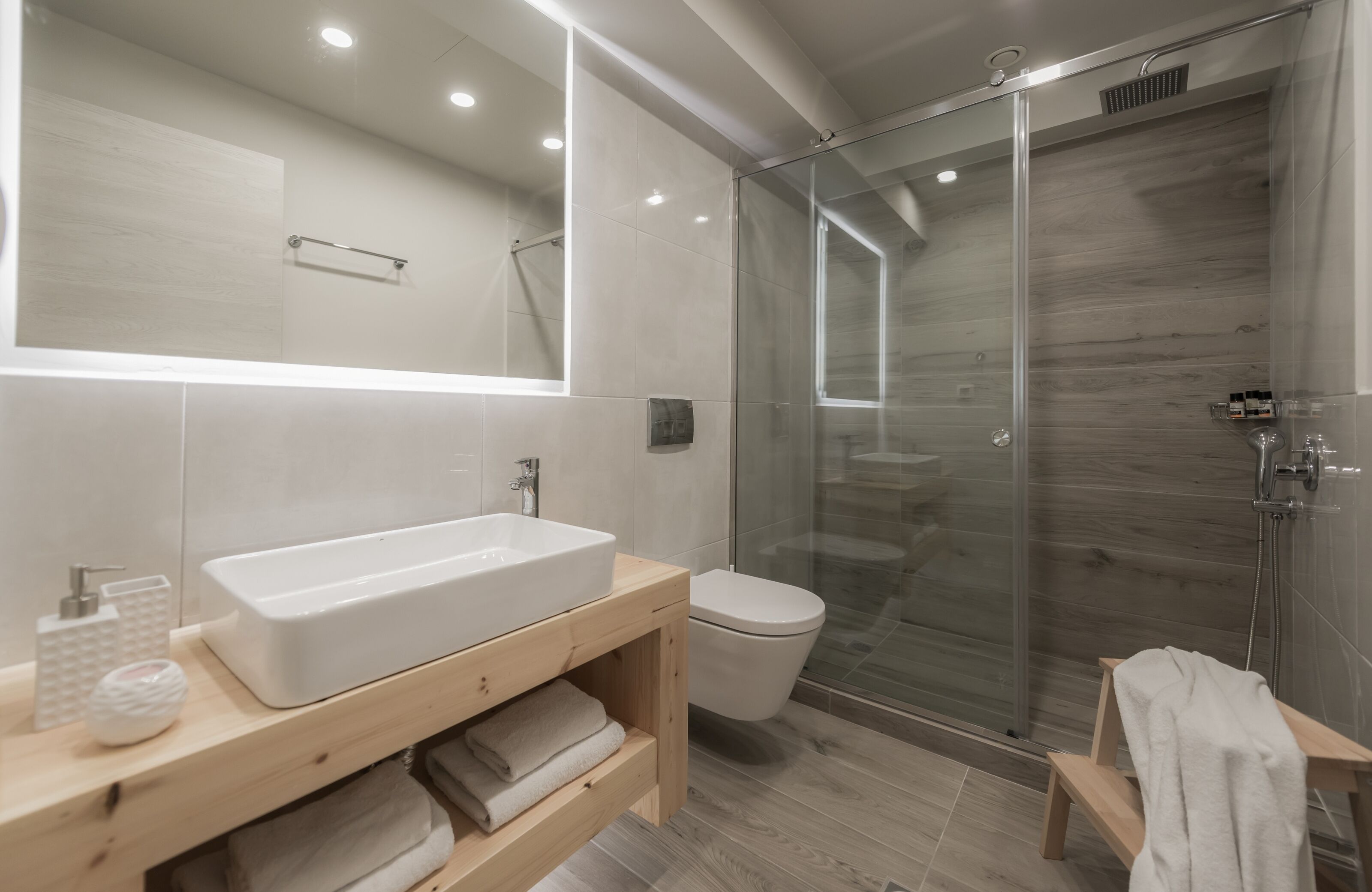 A modern bathroom with a large white sink, a toilet, and a glass-enclosed shower.