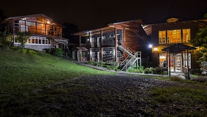 A modern two-story building with large windows and a staircase leading to the upper floor. - Hotel Bosque Verde Lodge (Sierra)