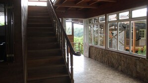 A wooden staircase with a stone wall and large windows. - Hotel Bosque Verde Lodge (Sierra)