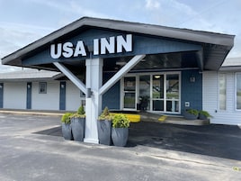 Edificio de USA Inn con fachada oscura, ventanas grandes y un letrero sobre la entrada.