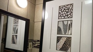 A bathroom with a mirror, tiled walls, and framed artwork.