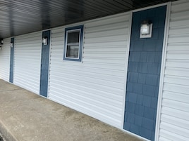 Un edificio con revestimiento blanco y detalles azules, incluyendo la puerta y los marcos de las ventanas.
