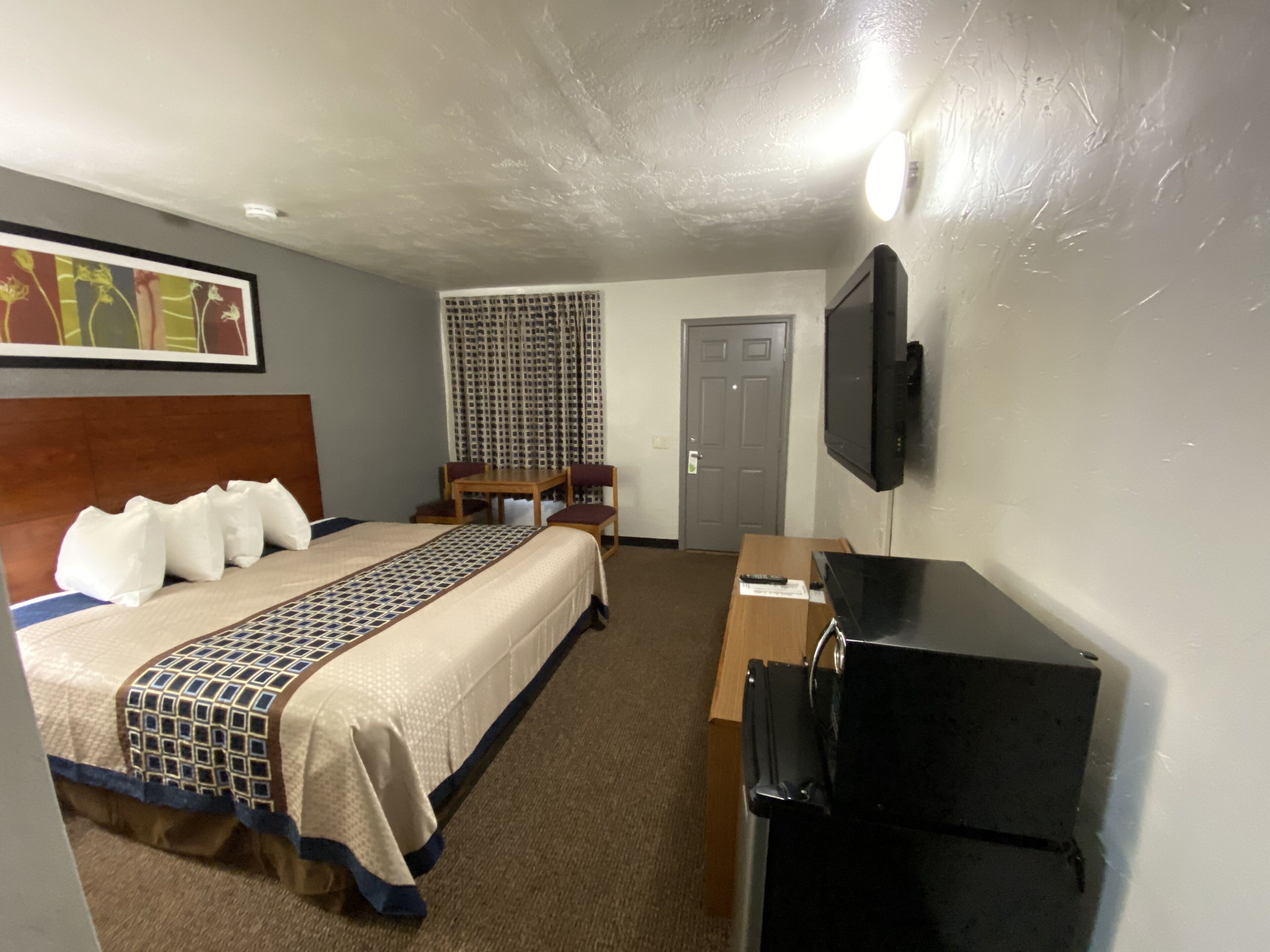 A hotel room with a bed, a desk, a television, and a window with curtains.