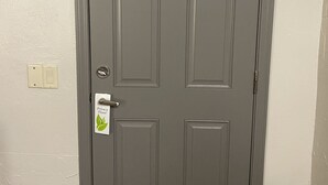 Puerta gris cerrada con letrero de privacidad y un interruptor de luz en la pared.