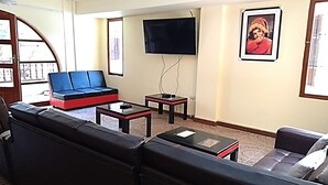 Una sala de estar con sofá, una mesa de centro, televisor y un cuadro en la pared.