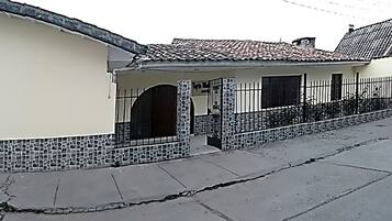 Un bâtiment à deux étages, doté d’un toit recouvert de tuiles, d’une porte de garage en bois et d’une base en pierre.