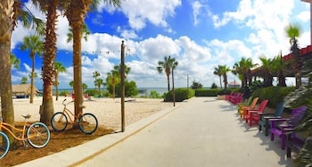 A covered outdoor lounge area with wicker furniture, a pool, and a view of the beach and marina. at The Beach Club at Charleston Harbor Resort and Marina