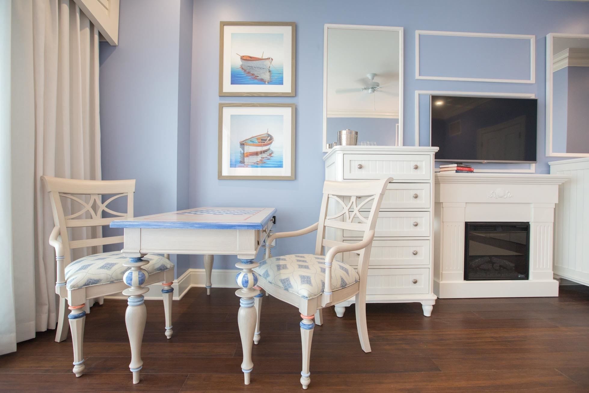 Una habitación con una mesa y sillas de madera, un aparador blanco y dos cuadros en la pared.