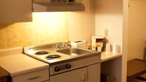 A compact kitchen with a stove, sink, and cabinets. - Circle 5 Motel (Olds)