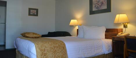 Habitación de hotel con cama, dos lámparas de noche, un teléfono, una silla y un cuadro en la pared.