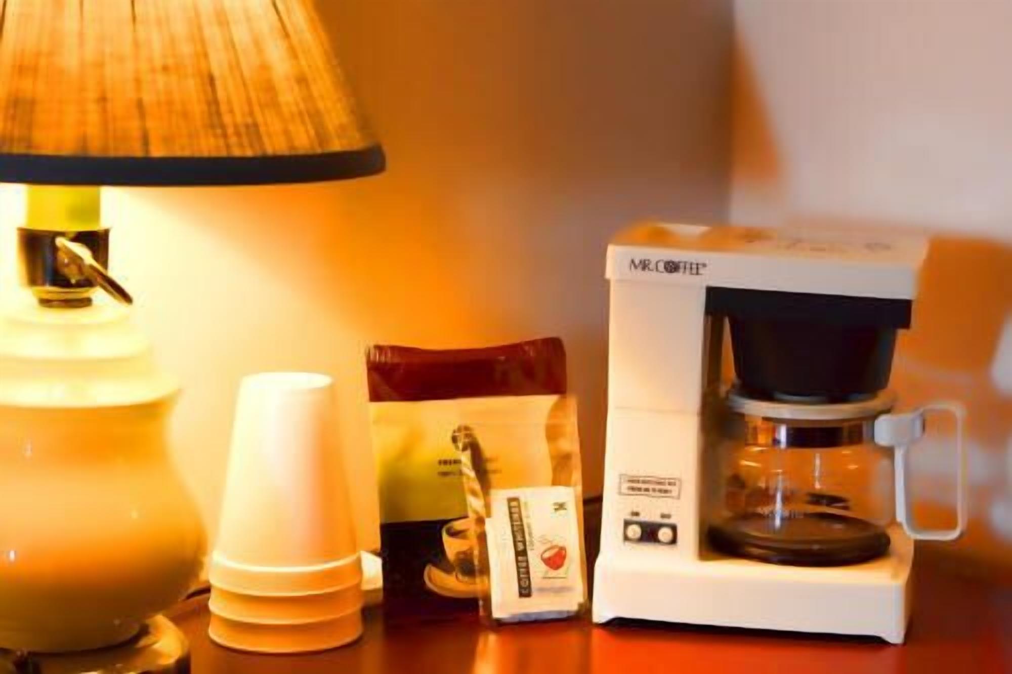 Una cafetera, una lámpara y una cápsula de café sobre una mesa.