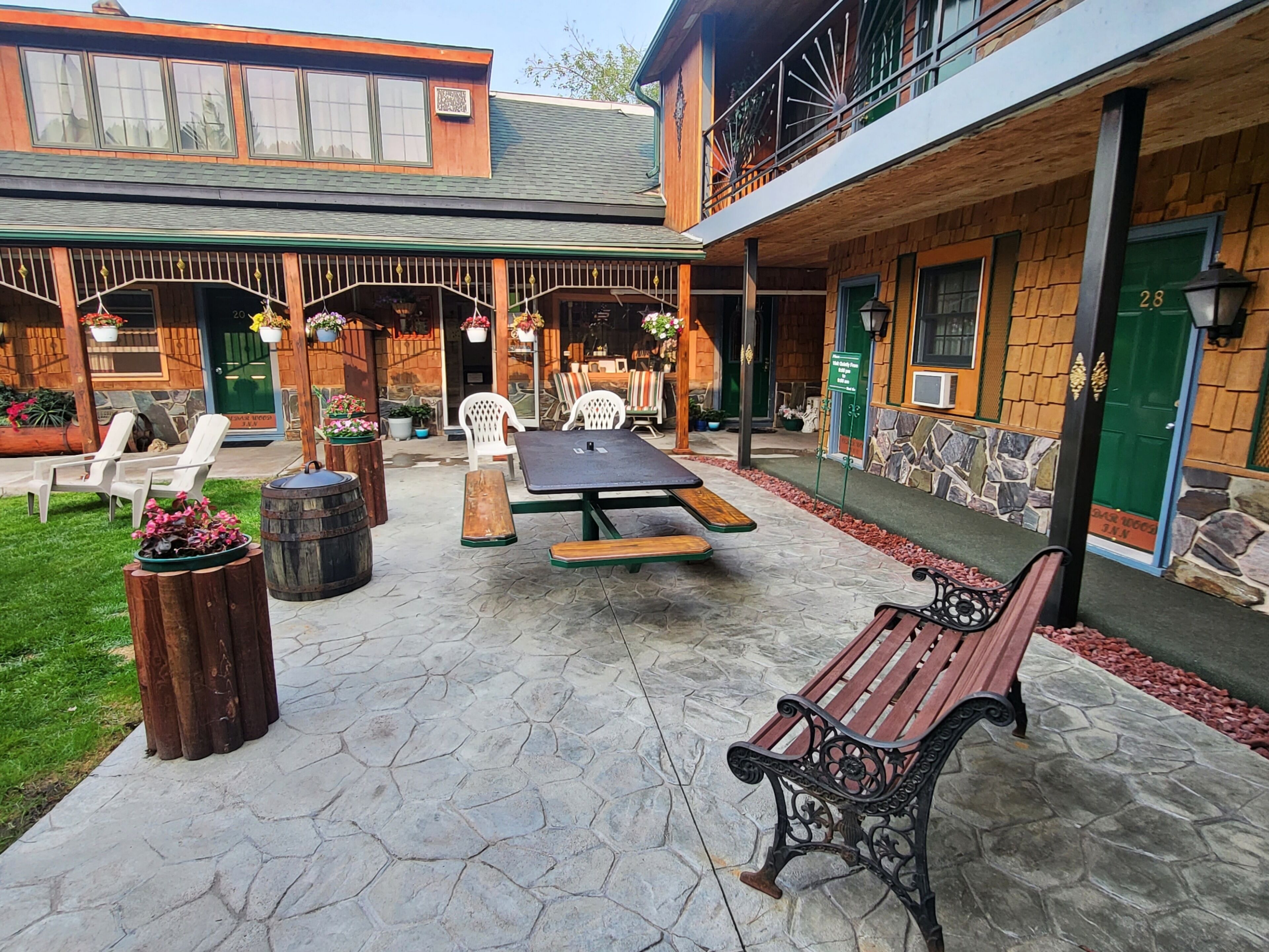 Un patio al aire libre con un banco de madera, una mesa de picnic y sillas blancas.