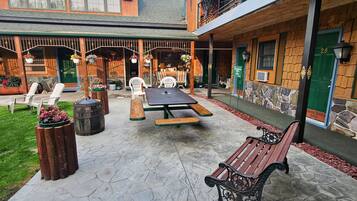 Un patio al aire libre con un banco de madera, una mesa de picnic y sillas blancas.