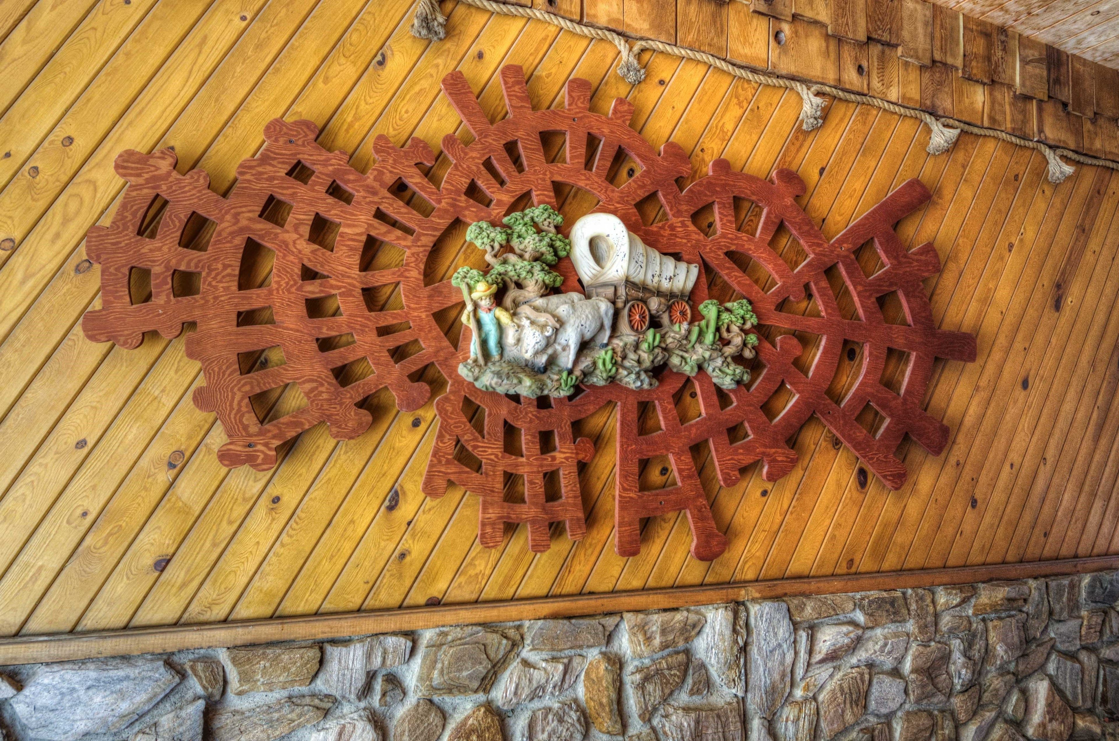 Techo de madera con un engranaje metálico decorativo y una pared de piedra.