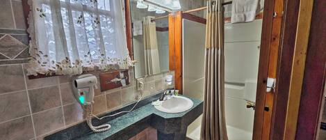 A bathroom with a sink, mirror, and shower.