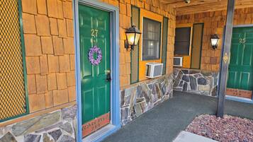 A building with a stone and wooden facade, numbered doors, and a stone pathway leading to the entrance.