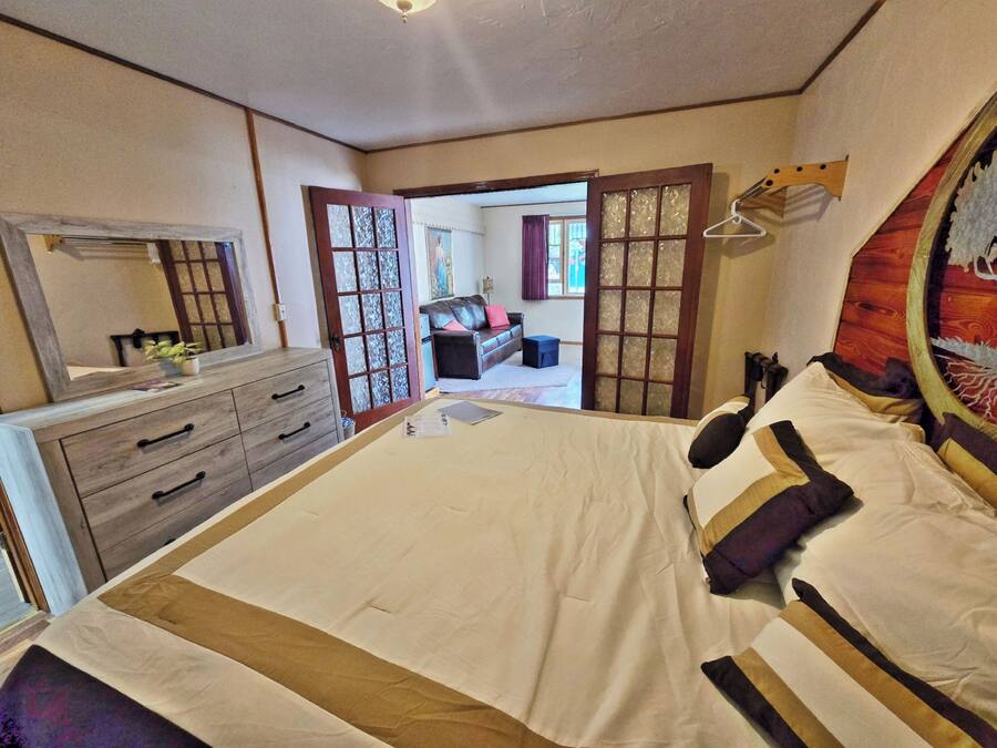 Un dormitorio con una cama grande, un aparador y un espejo. Hay una puerta que conduce a otra habitación.