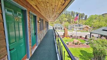 A wooden porch with green doors numbered 15 and 14, leading to a covered walkway.
