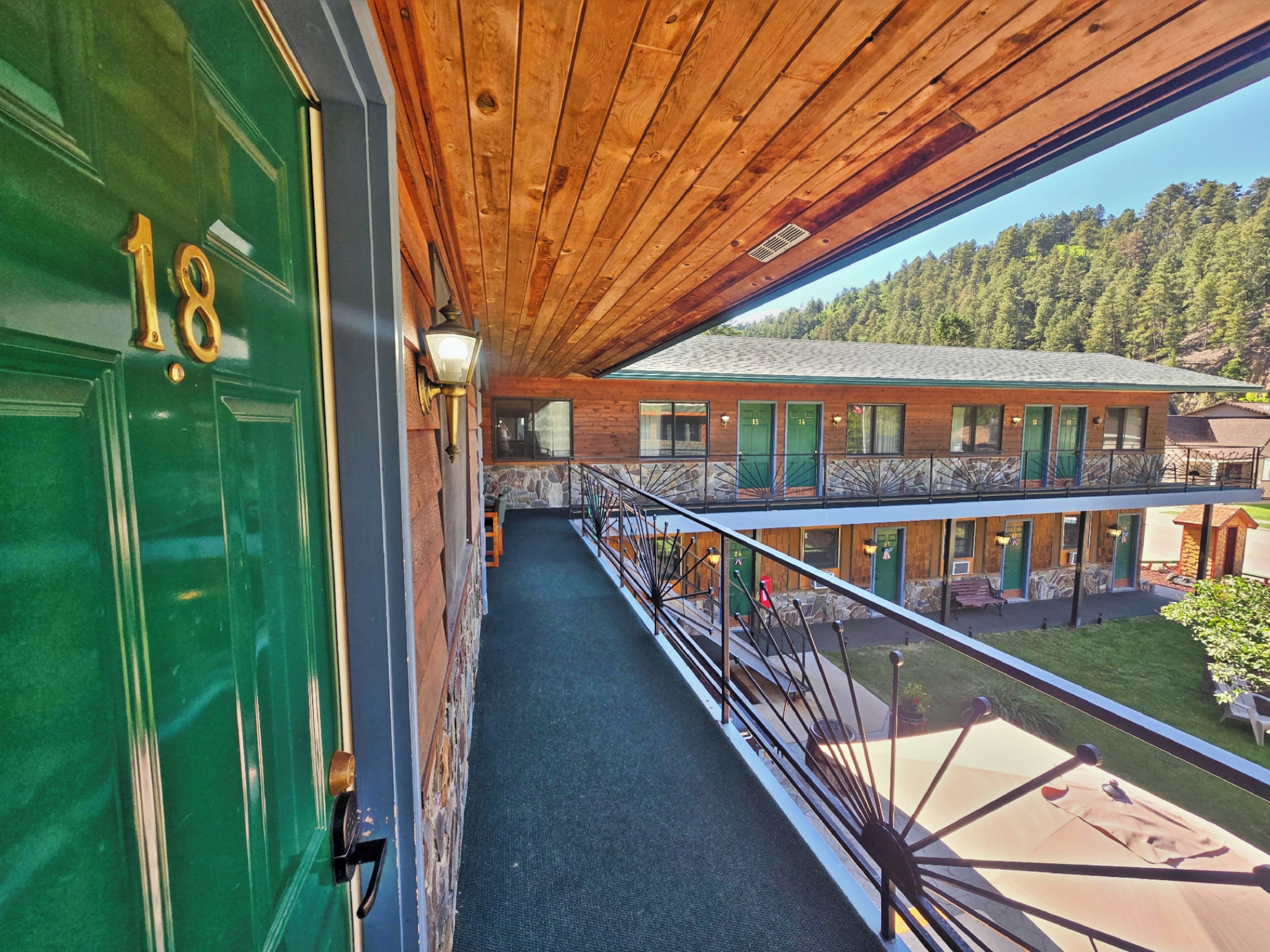 A wooden balcony with a view of a building and forest.