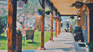 A covered outdoor area with wooden pillars, hanging flower baskets, and a pathway leading to a building labeled "OFFICE". - Cedar Wood Inn (Deadwood)