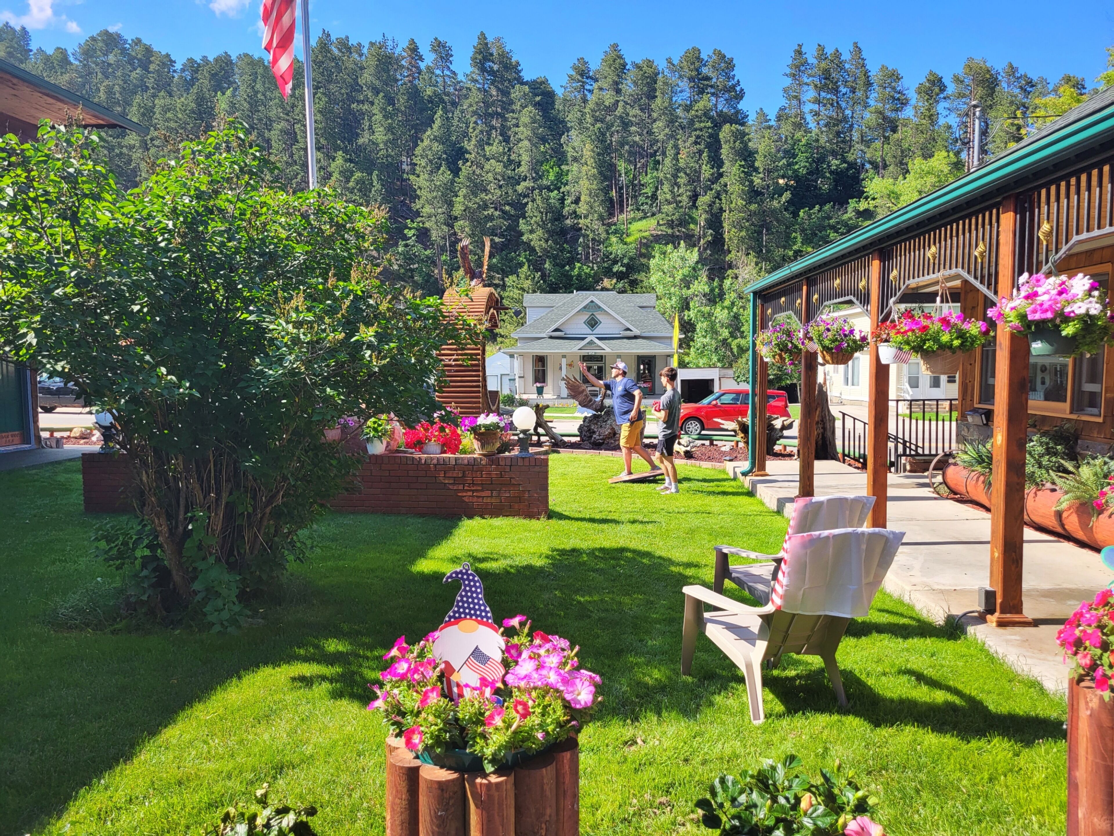 A well-maintained garden with a wooden pergola, outdoor seating, and a flag.