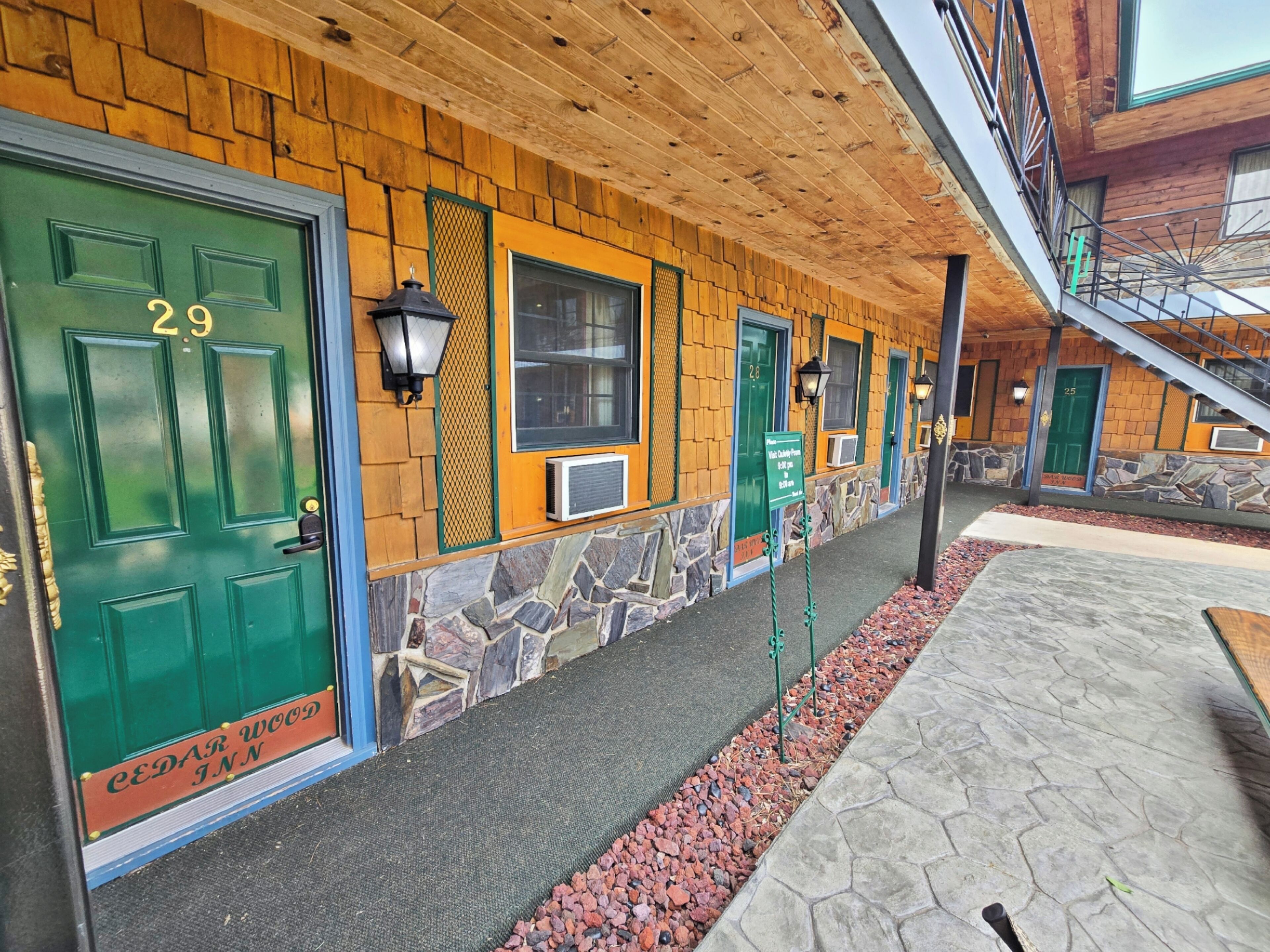 A building with multiple green doors, each labeled with a number. The exterior features wooden siding and stone accents.
