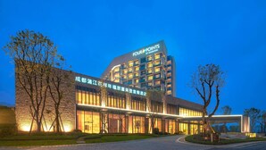 Un hotel moderno con un llamativo letrero de 'Four Points by Sheraton', que presenta un diseño contemporáneo con grandes ventanales y una entrada bien iluminada.
