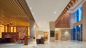 Un hall espacioso con techo alto, paneles de madera y mostrador de recepción.
