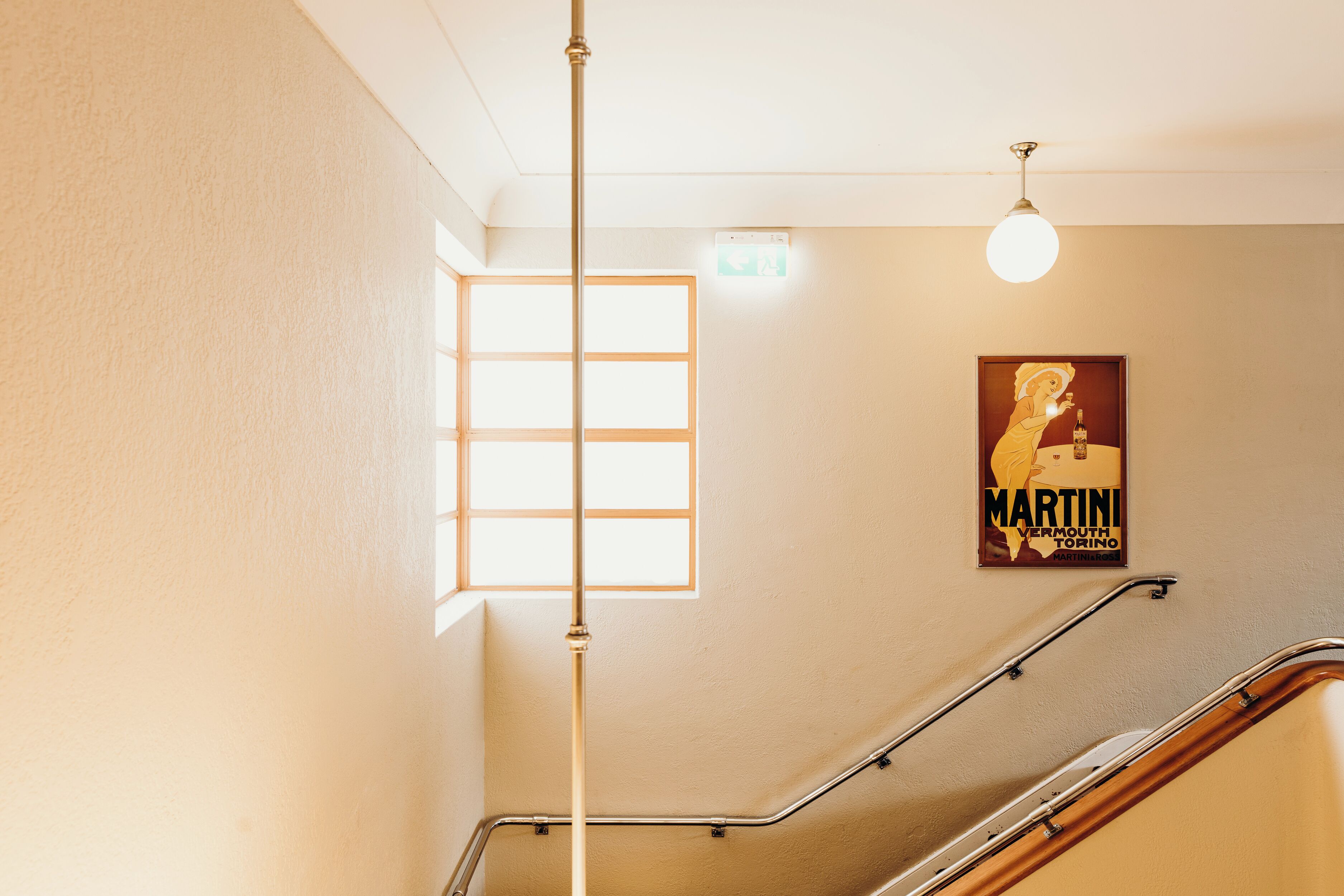 A staircase with metal handrails, a light fixture, and a poster on the wall.