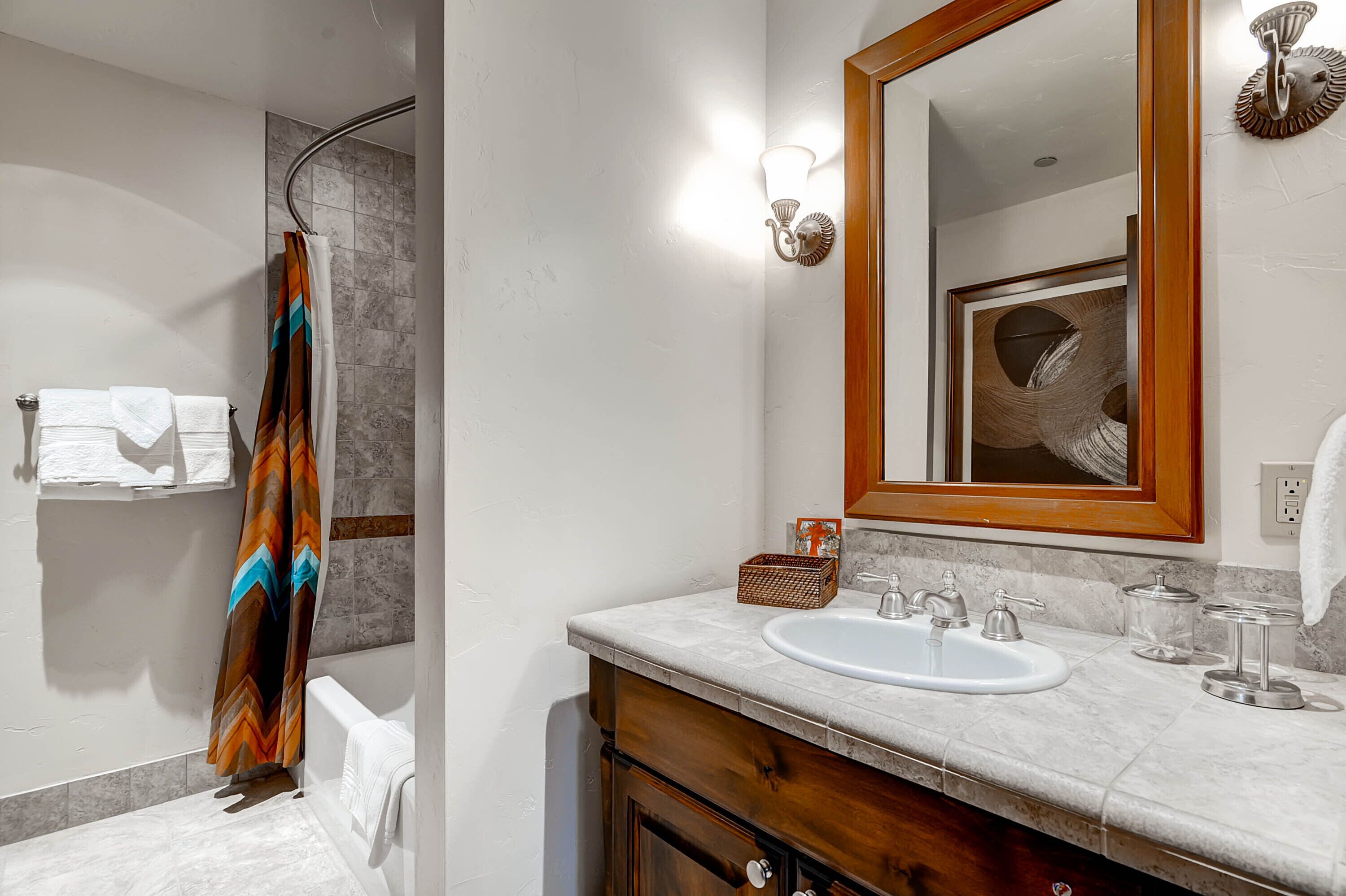 Un bagno con doccia, lavandino, specchio e portasciugamani.