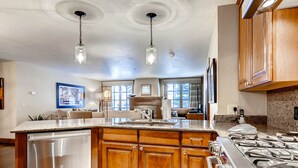 A spacious kitchen with wooden cabinets, a stainless steel dishwasher, and a gas stove. - Ascent by East West Hospitality (Avon)