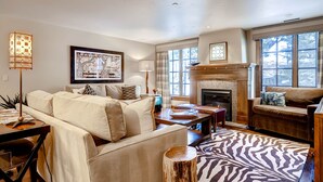 A cozy living room with a fireplace, a sofa, a coffee table, and a zebra-patterned rug. - Ascent by East West Hospitality (Avon)