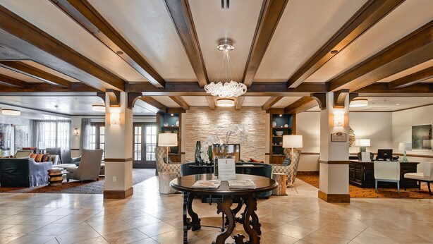 A spacious lobby with a round table, seating area, and a stone accent wall. - Ascent by East West Hospitality (Avon)