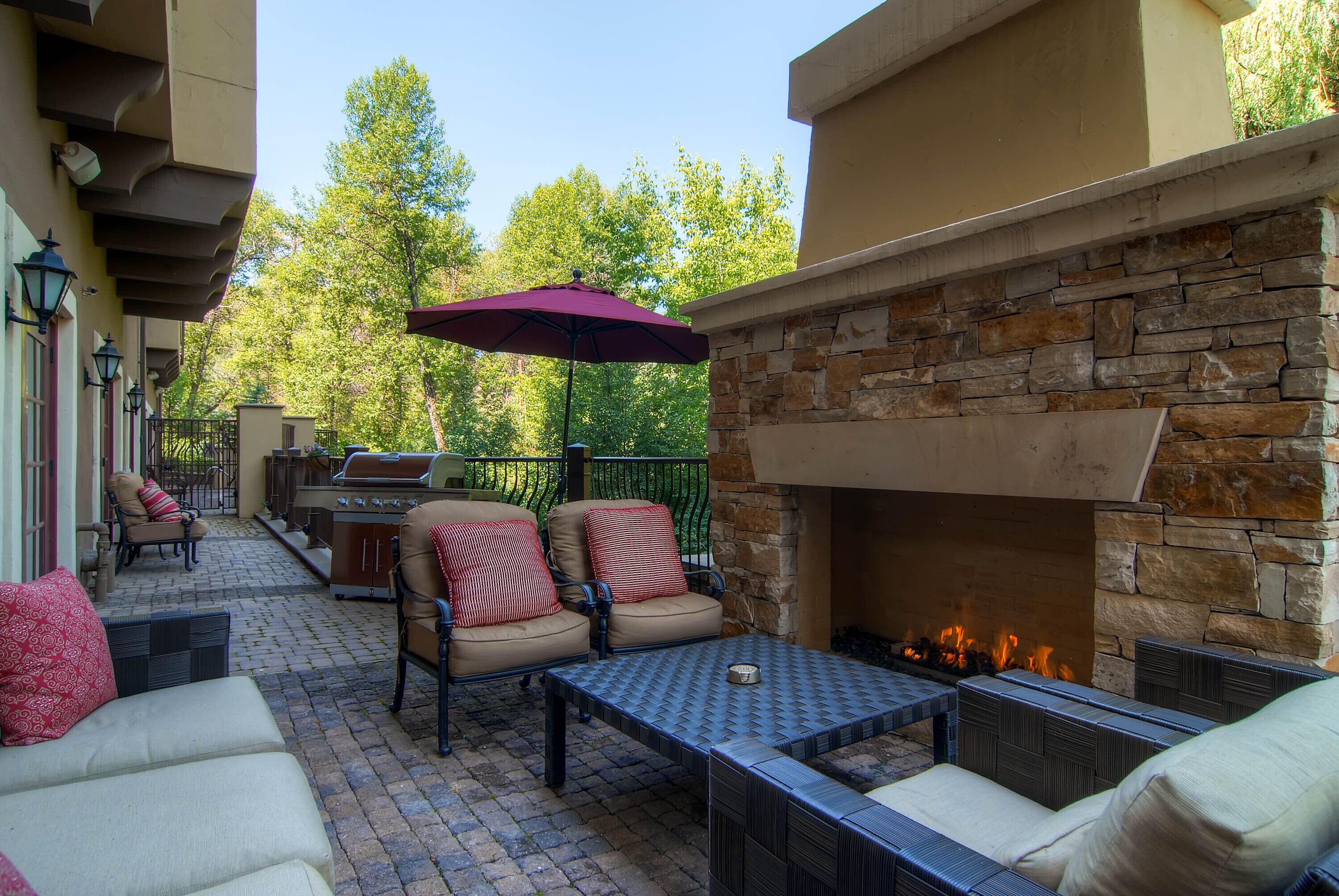 An outdoor patio with stone walls, a fire pit, and outdoor furniture.