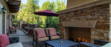 An outdoor patio with stone walls, a fire pit, and outdoor furniture.