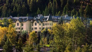A row of multi-story buildings with a uniform architectural style, surrounded by dense forest. - Ascent by East West Hospitality (Avon)