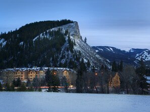 A hotel with multiple buildings, a snowy mountain backdrop, and a forested area. - Ascent by East West Hospitality (Avon)