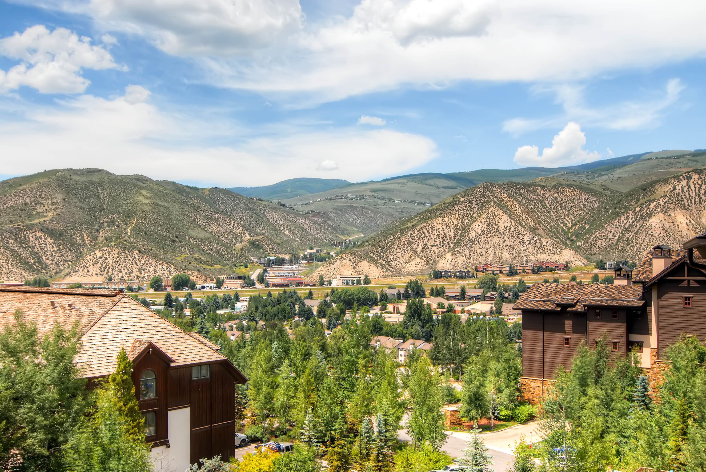 A residential area with houses, a road, and mountains in the background.