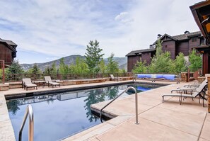 Un espace piscine avec des chaises longues et une vue sur les montagnes.