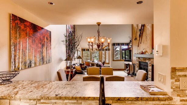 A spacious living room with a large painting, a dining area with a marble island, and a fireplace.