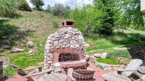 A stone outdoor fireplace with wooden chairs and a table.