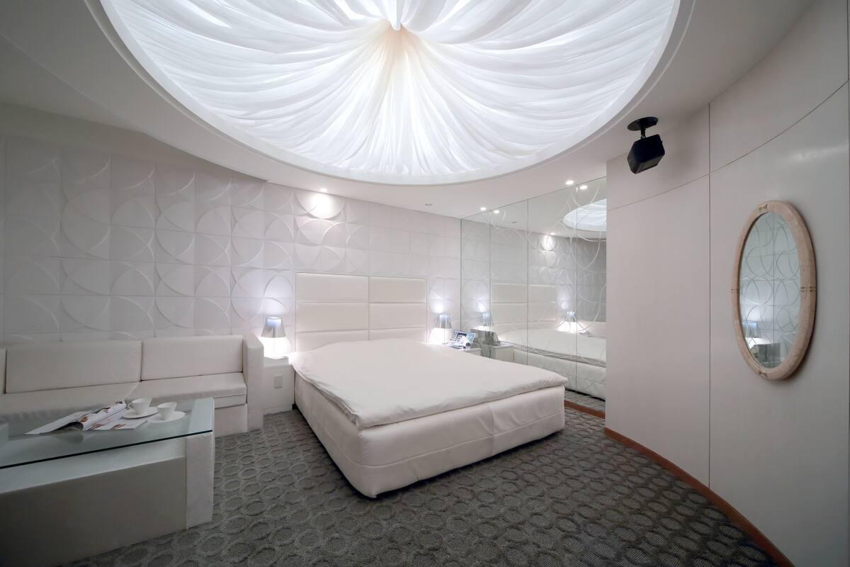 A modern bathroom with a large mirror, a round mirror, and a ceiling light fixture.