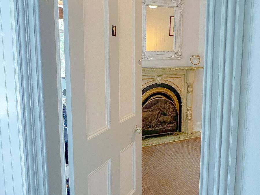 Una habitación con chimenea, una puerta con número y una alfombra estampada.