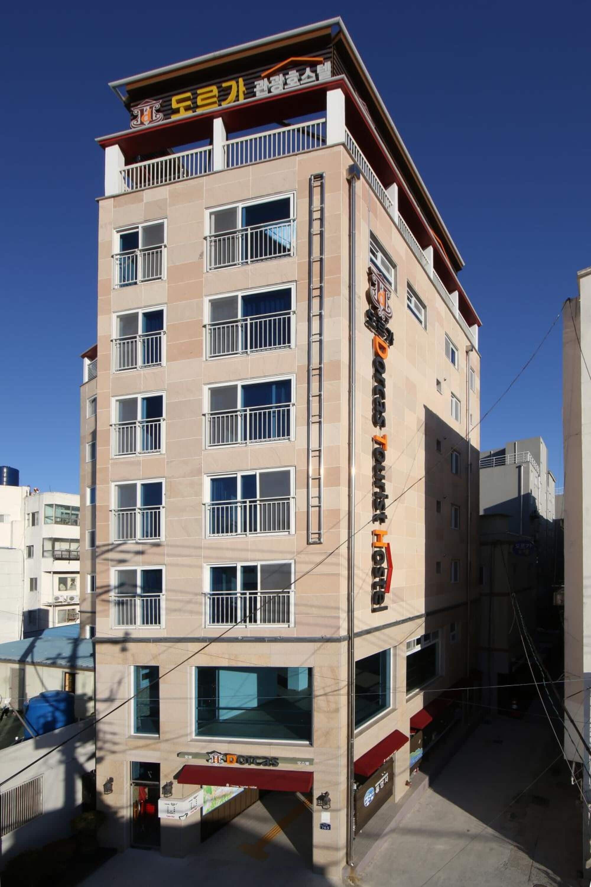 A multi-story hotel with a modern design, featuring balconies on each floor and a prominent sign on the facade.
