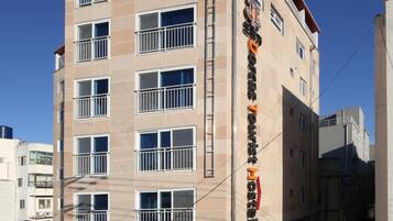 A multi-story hotel with a modern design, featuring balconies on each floor and a prominent sign on the facade.