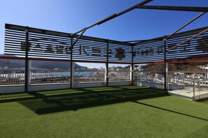 En modern arkitektonisk konstruktion med en stomme av metall och glaspaneler, som erbjuder utsikt över en kuststad.