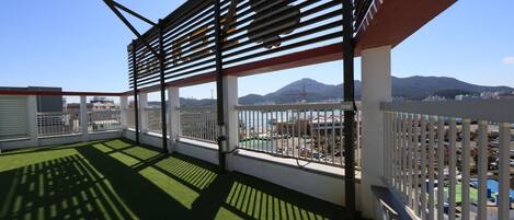 A balcony with a view of mountains and a cityscape.